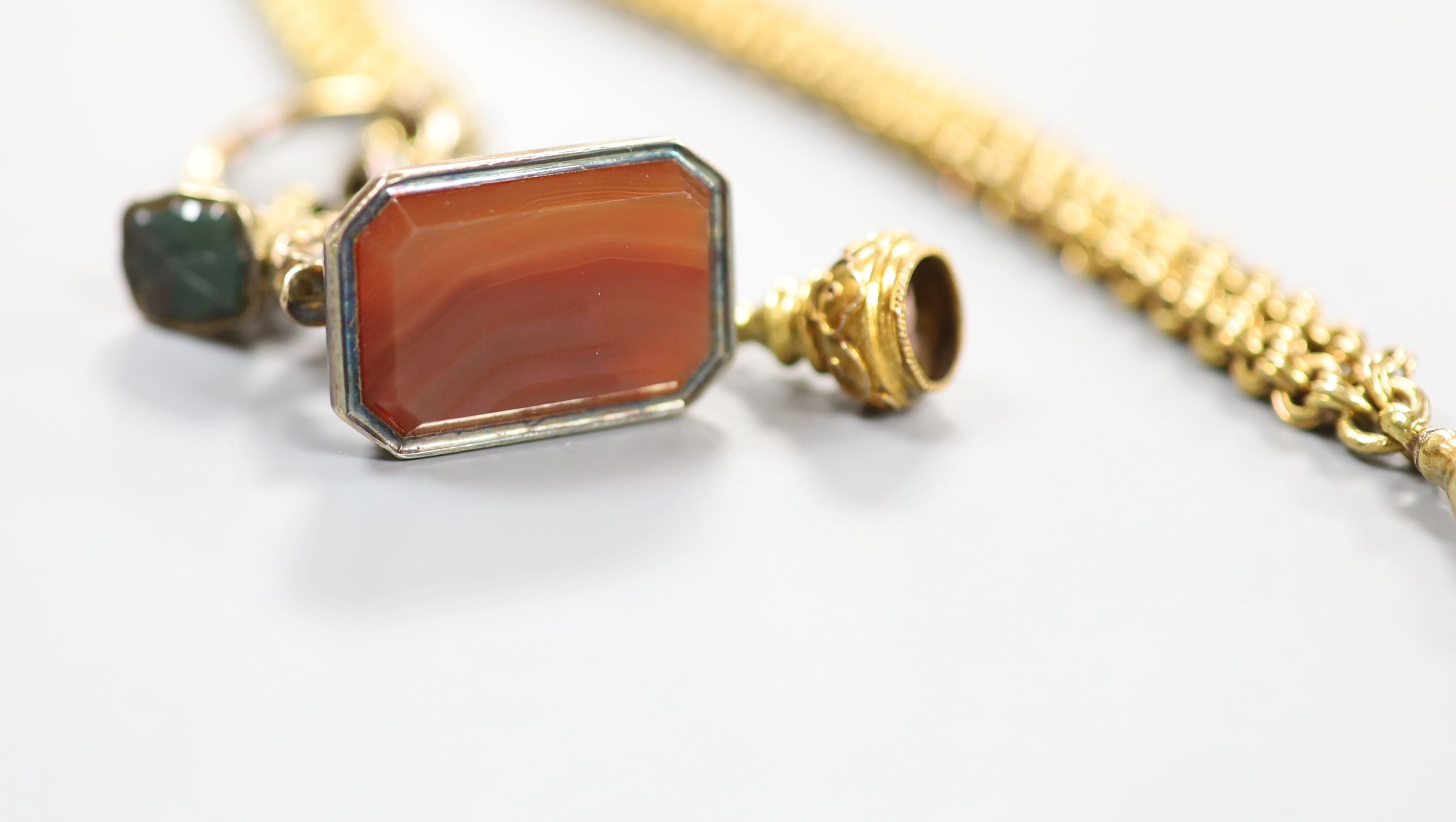 Two gilt metal and chalcedony set fob seals, (agate and bloodstone) and one other seal, all hung from a gilt metal chain.